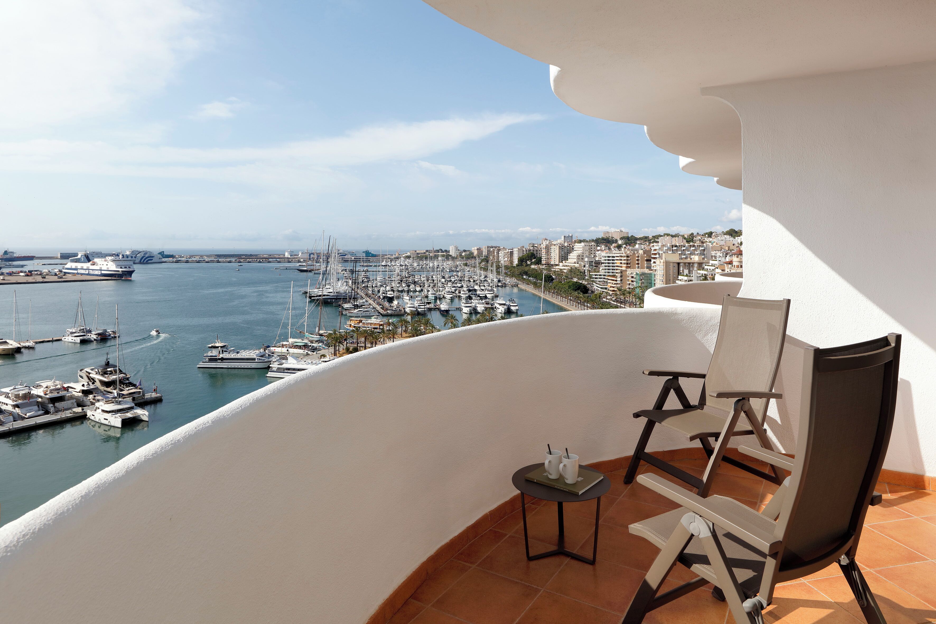 Un balcón con vista a un puerto deportivo y al paisaje urbano.
