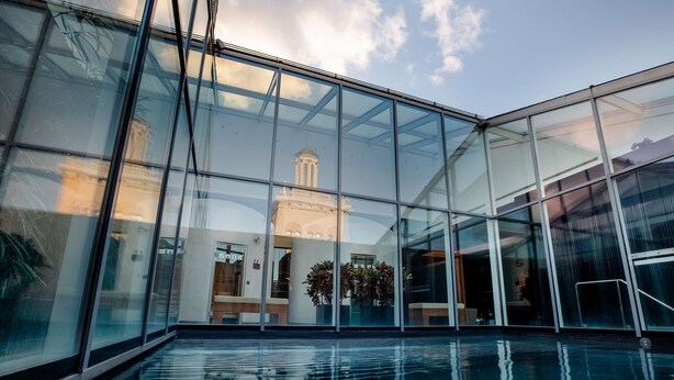 A modern building with large glass windows reflecting a building with columns.