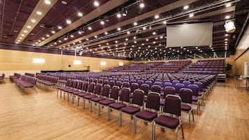 Un grand auditorium avec des rangées de chaises violettes et un plancher en bois.
