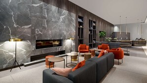 A modern living room with a fireplace, seating area, and built-in bookshelves.