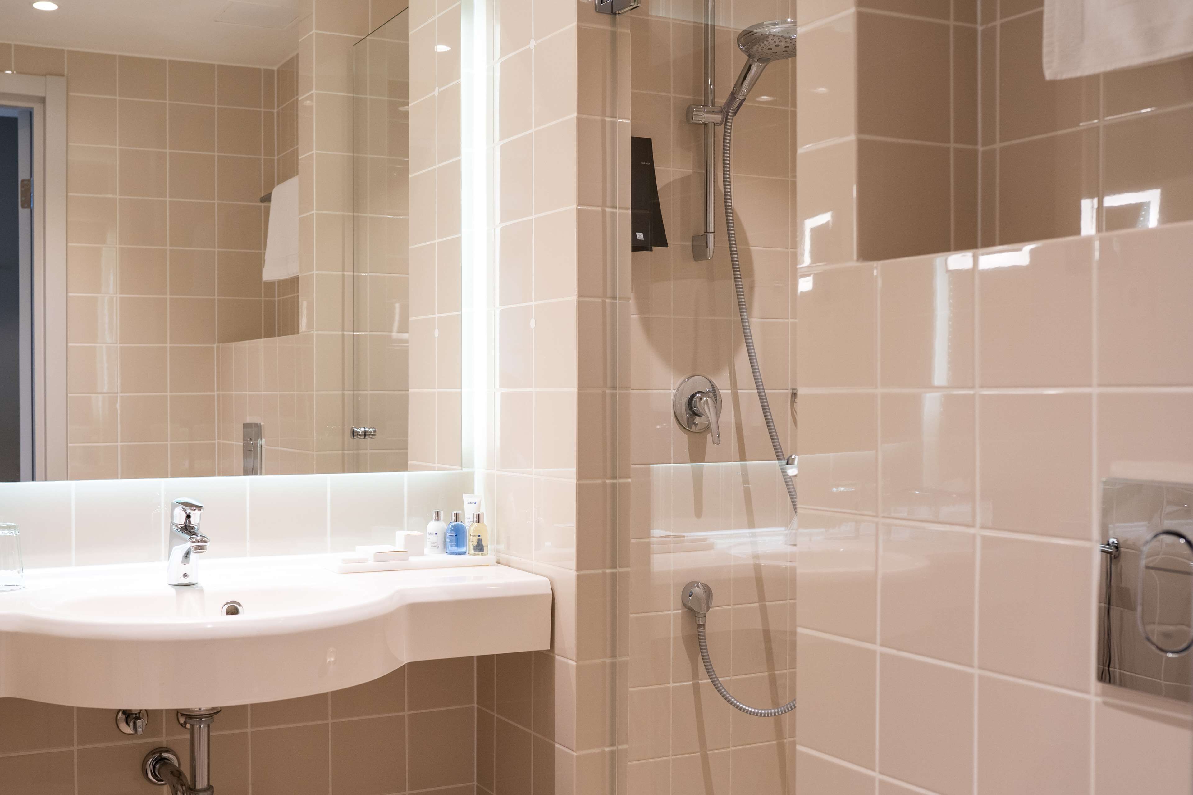 A modern bathroom with a sink, mirror, and shower.