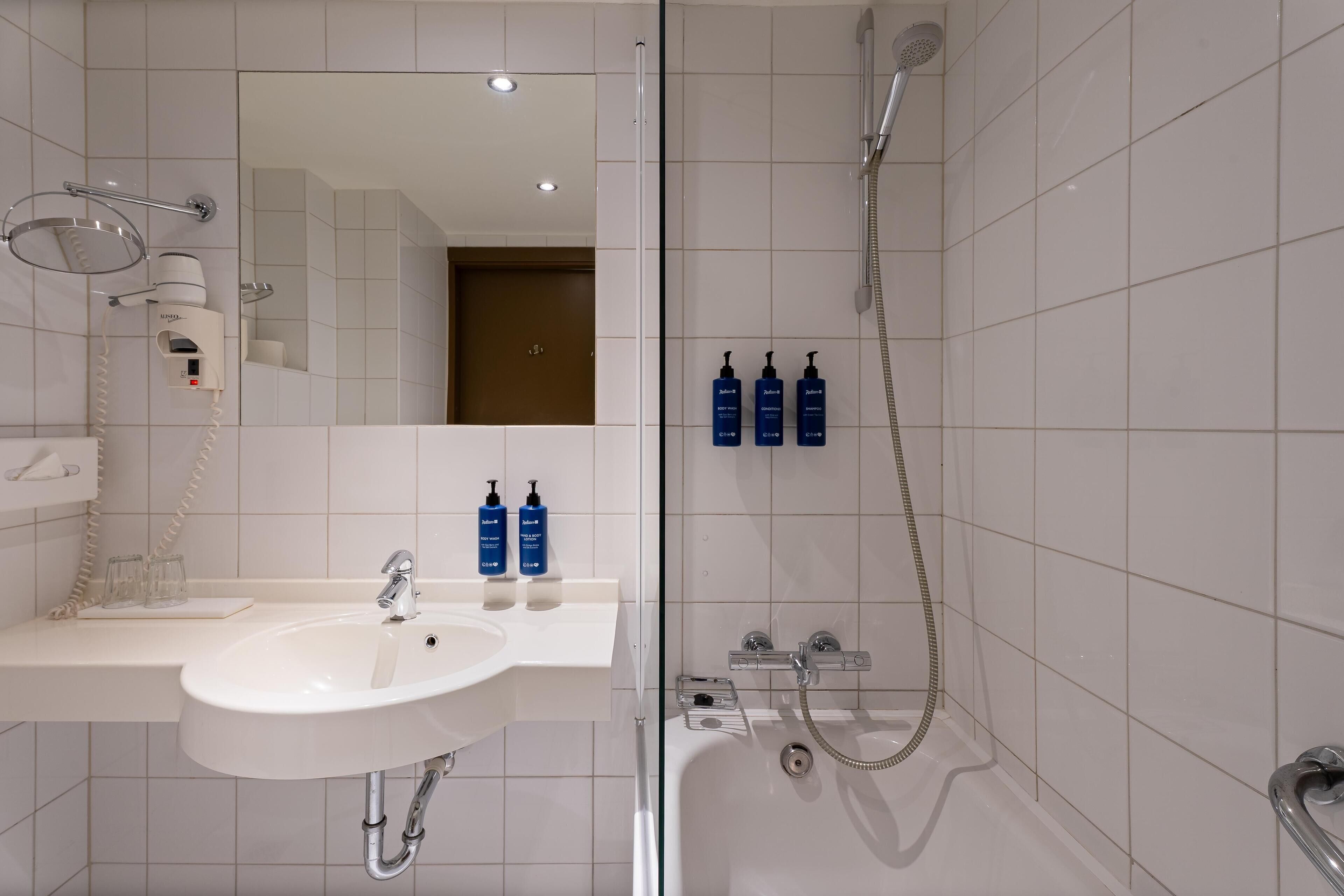 Een moderne badkamer met een wastafel, spiegel en douche.