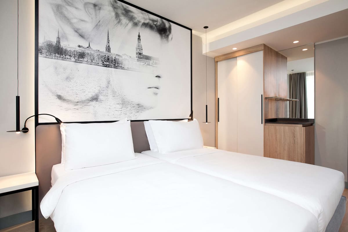 Una habitación de hotel moderna con una cama grande, vistas a un paisaje urbano y una pequeña kitchenette.