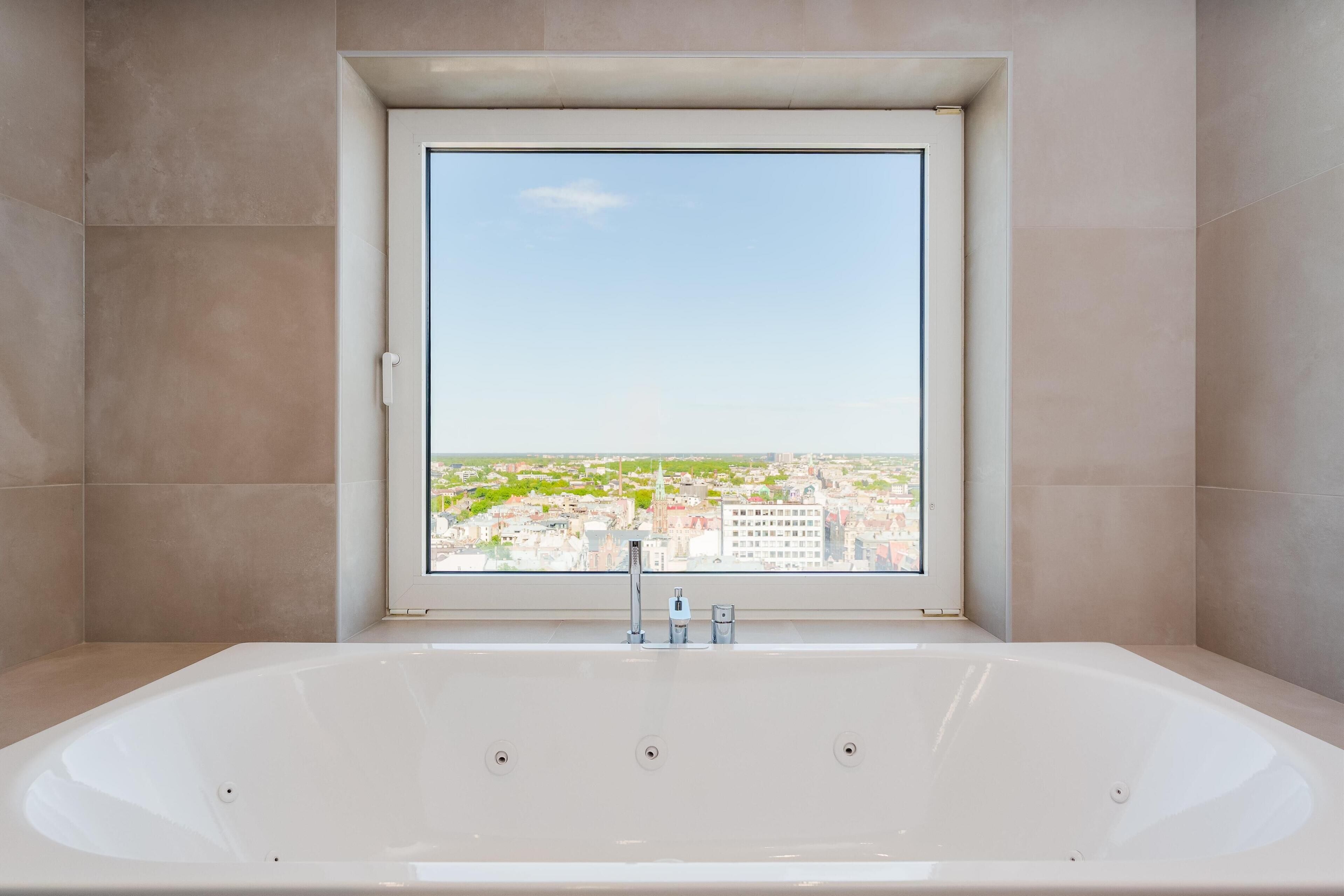 Ein modernes Badezimmer mit einer großen Badewanne, einem Fenster mit Blick auf die Stadt und einer Duschkabine.