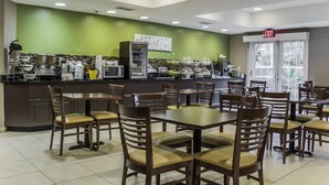 A restaurant with a green wall, a counter with various food items, and multiple tables and chairs. - Sleep Inn Charleston - West Ashley (Charleston)