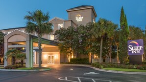 A Sleep Inn hotel with a well-lit entrance, palm trees, and a clear sky. - Sleep Inn Charleston - West Ashley (Charleston)