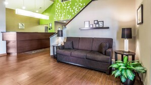 A reception area with a wooden floor, a reception desk, a sofa, a staircase, and a potted plant. - Sleep Inn Charleston - West Ashley (Charleston)