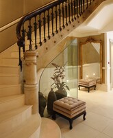 Eine imposante Treppe mit Glastrennwand, ein Samt-Pouff und ein großer Spiegel.