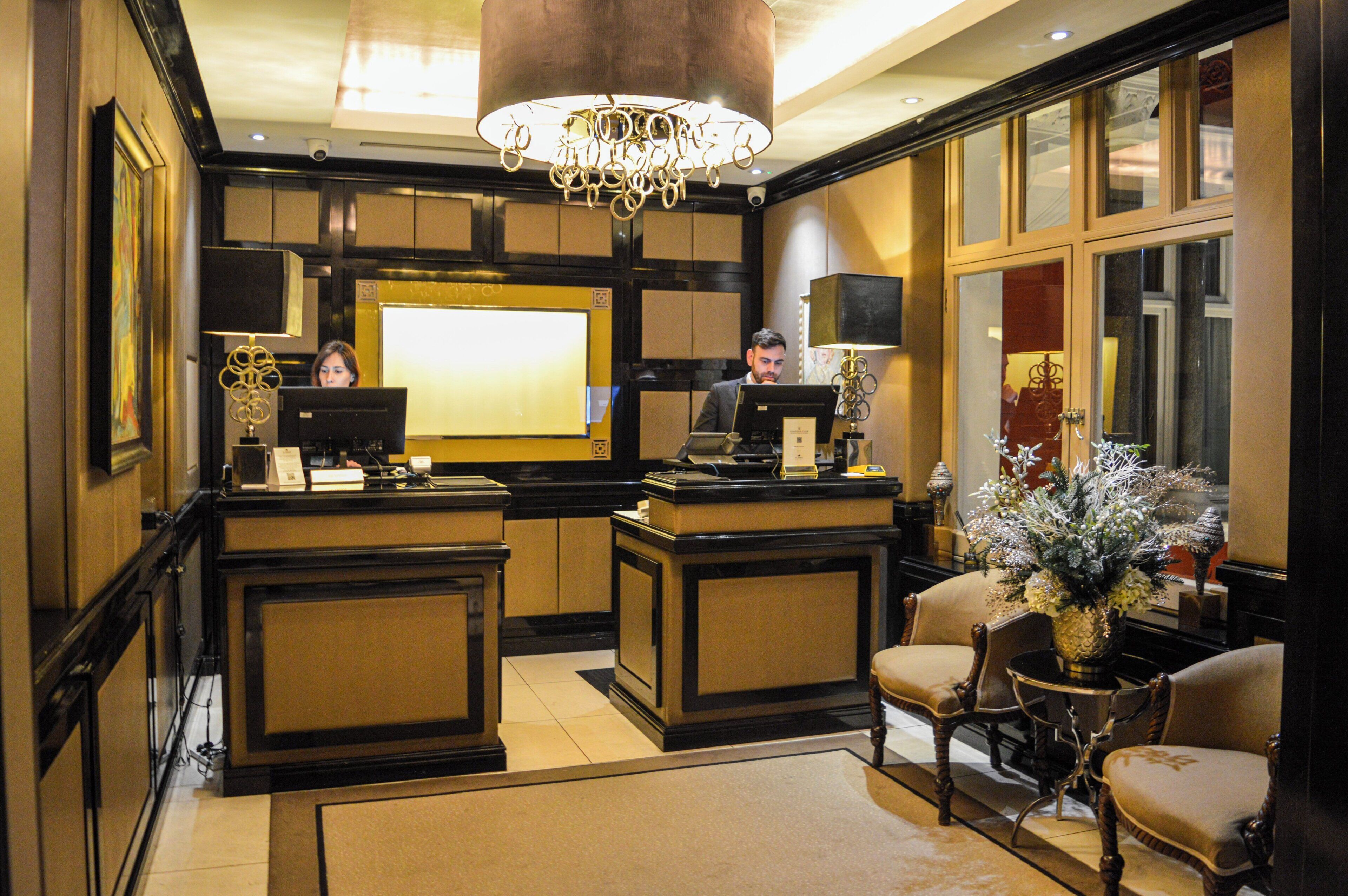 A reception area with a desk, chairs, a chandelier, and a large window.