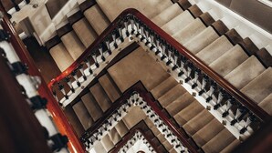 A multi-level interior with a central staircase, carpeted steps, and a wooden handrail. - Althoff St. James's Hotel & Club London (London)