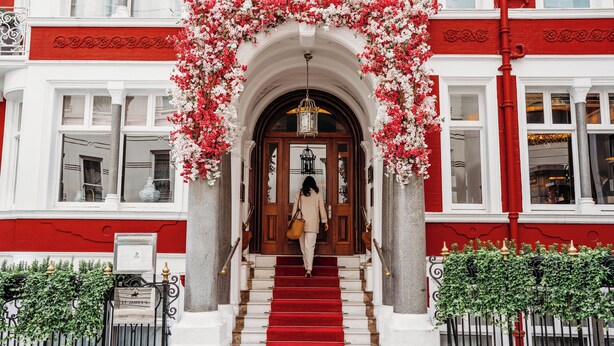 A building entrance with a red carpet, white walls, and a floral archway. - Althoff St. James's Hotel & Club London (London)