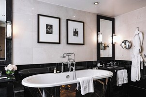 Ein modernes Badezimmer mit einer freistehenden Badewanne, einem großen Spiegel und gerahmten Bildern an der Wand.