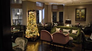 A well-lit living room with a Christmas tree, comfortable seating, and a large window. - Althoff St. James's Hotel & Club London (London)