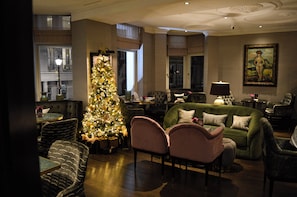 A well-lit living room with a Christmas tree, comfortable seating, and a large window. - Althoff St. James's Hotel & Club London (London)