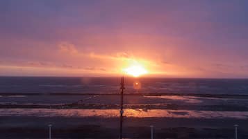 Un coucher de soleil sur l’océan, avec une jetée qui s’avance dans l’eau.
