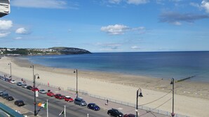 Ein Strand, parallel davon eine Straße mit parkenden Autos und Straßenlaternen.
