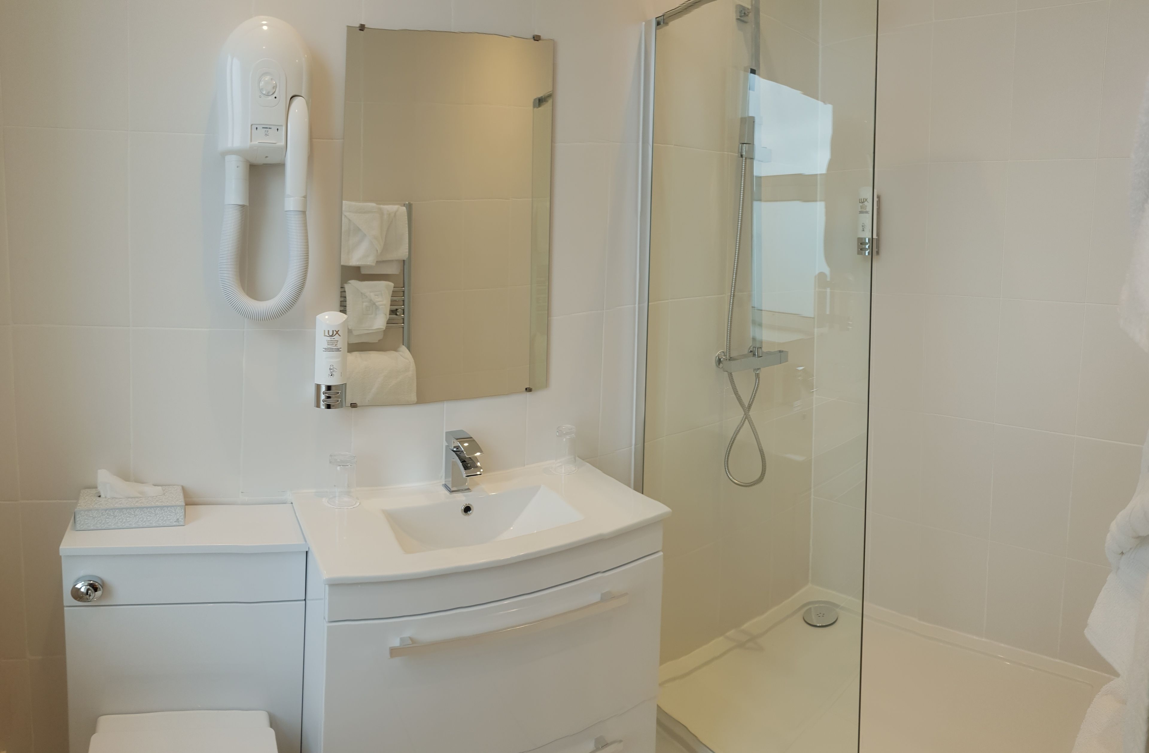 A modern bathroom with a white sink, vanity, and a glass-enclosed shower.