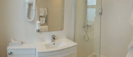 A modern bathroom with a white sink, vanity, and a glass-enclosed shower.