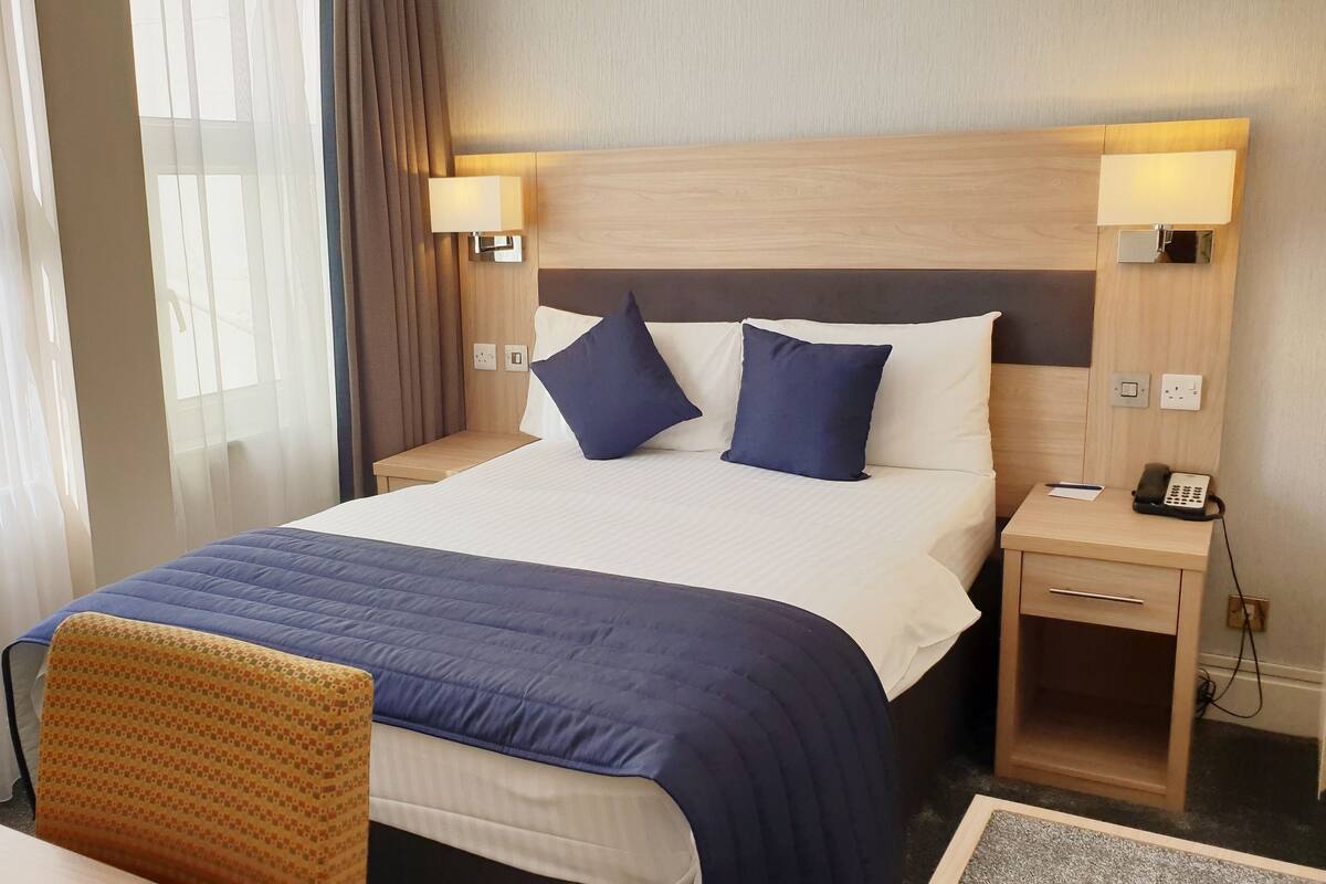 A hotel room with a large bed, two bedside tables, a desk, and a chair.
