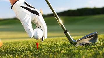 A golf club positioned over a tee on a grassy field.