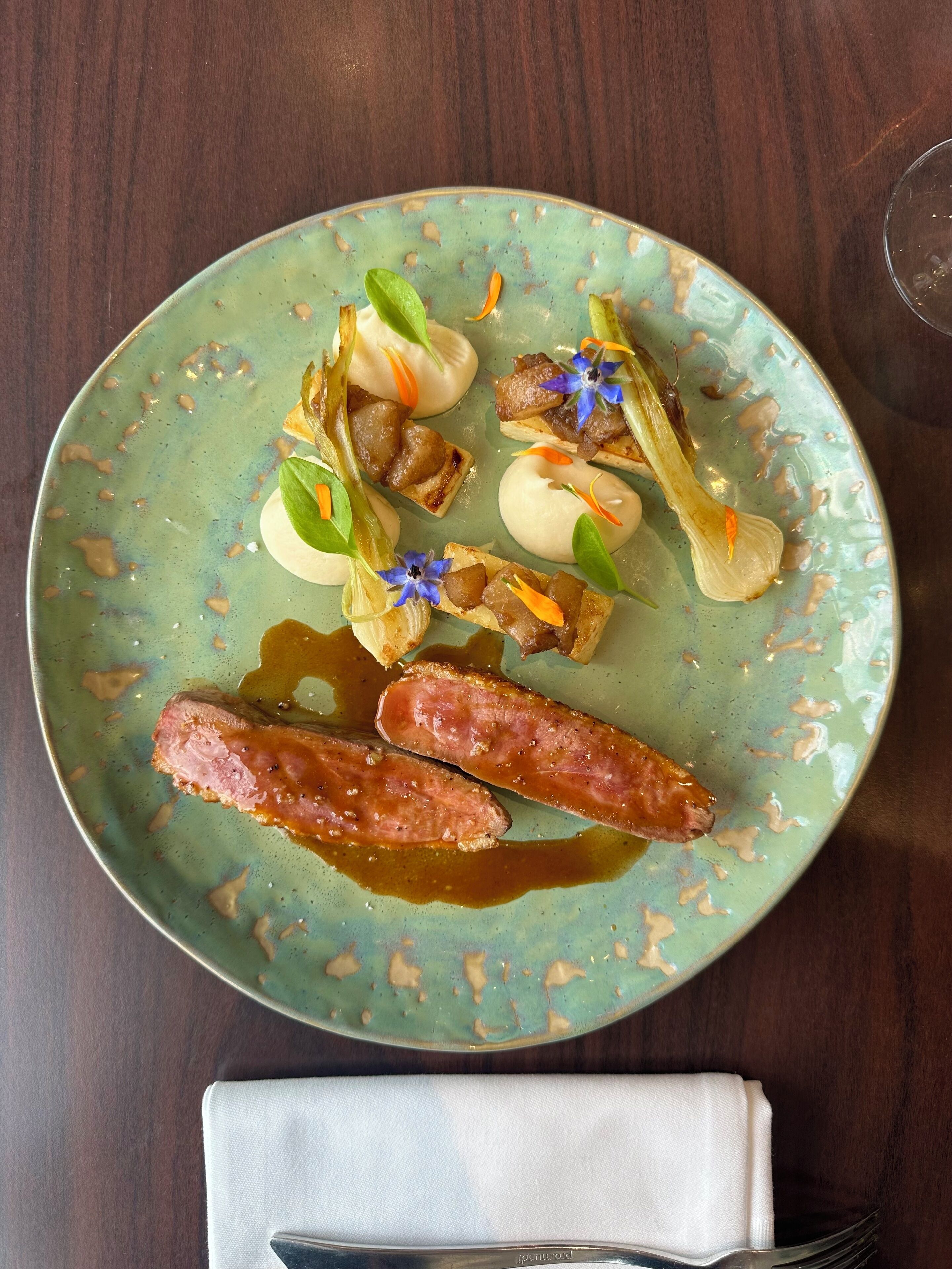 Une assiette remplie de différents aliments, notamment des saucisses, des légumes et une fleur décorative.