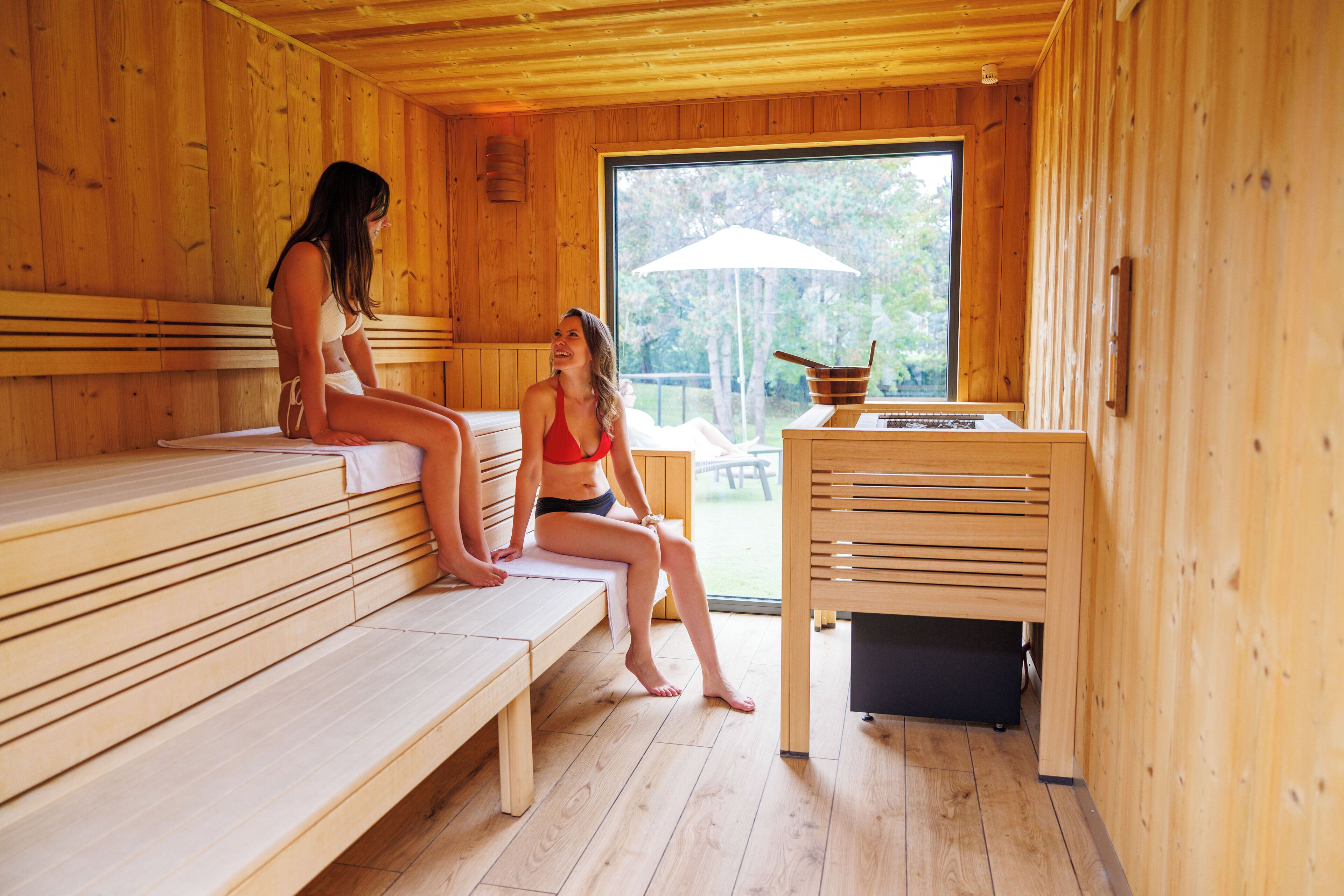 Un sauna avec des bancs en bois et une grande fenêtre.