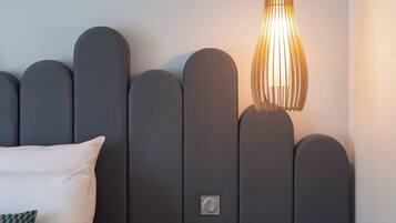A modern hotel room with a headboard featuring a unique design and a bedside table with a lamp.