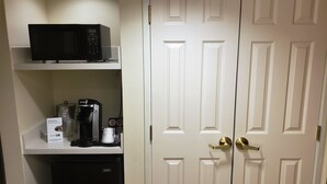 A kitchenette with a microwave, coffee maker, and refrigerator.