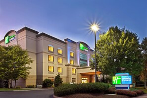 A Holiday Inn Express hotel with a modern facade, multiple windows, and a well-lit entrance. - Holiday Inn Express Portland West/Hillsboro by IHG (Hillsboro)