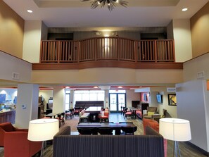 A hotel lobby with a dining area, seating arrangements, and a staircase leading to an upper level. - Holiday Inn Express Portland West/Hillsboro by IHG (Hillsboro)