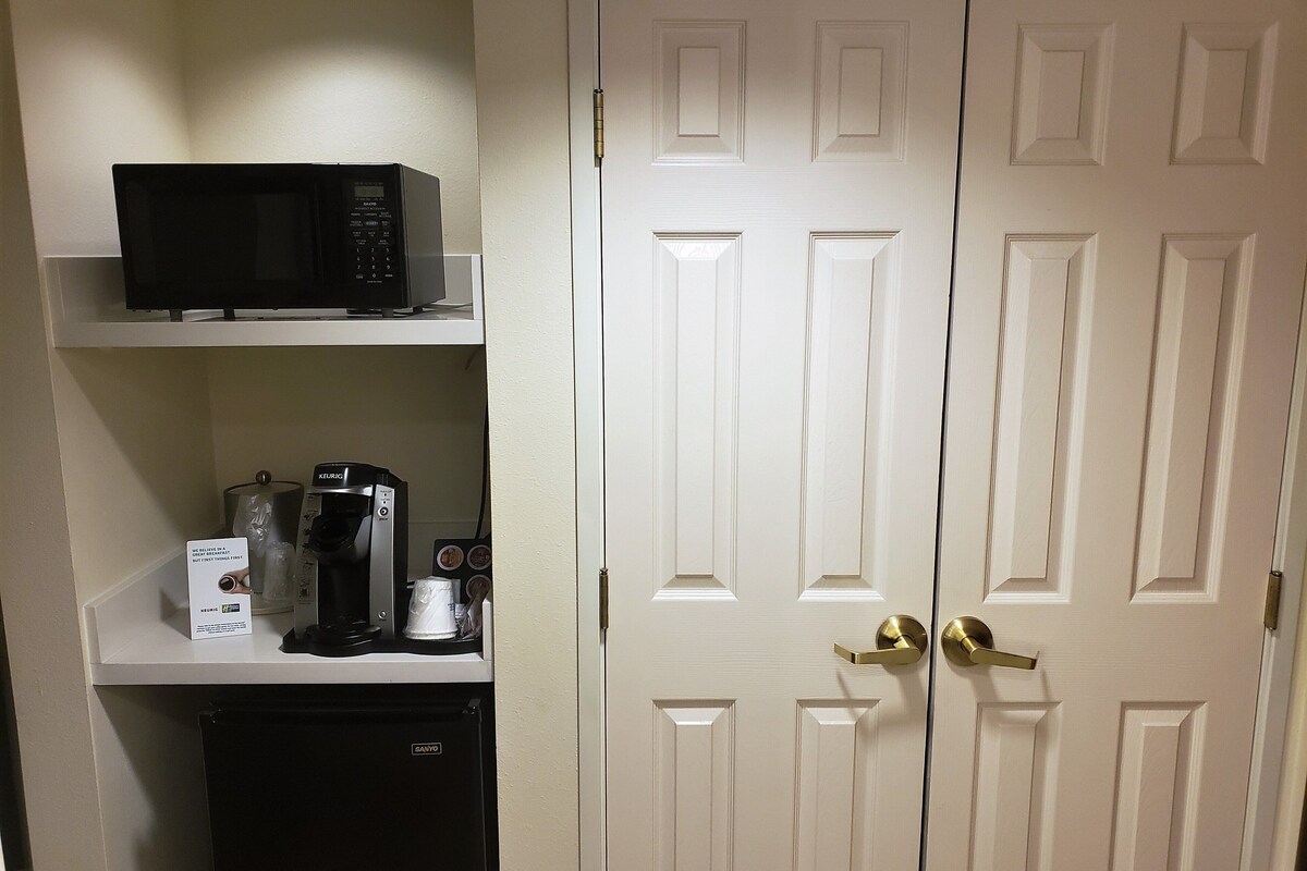 A compact kitchenette with a microwave, coffee maker, and a refrigerator.