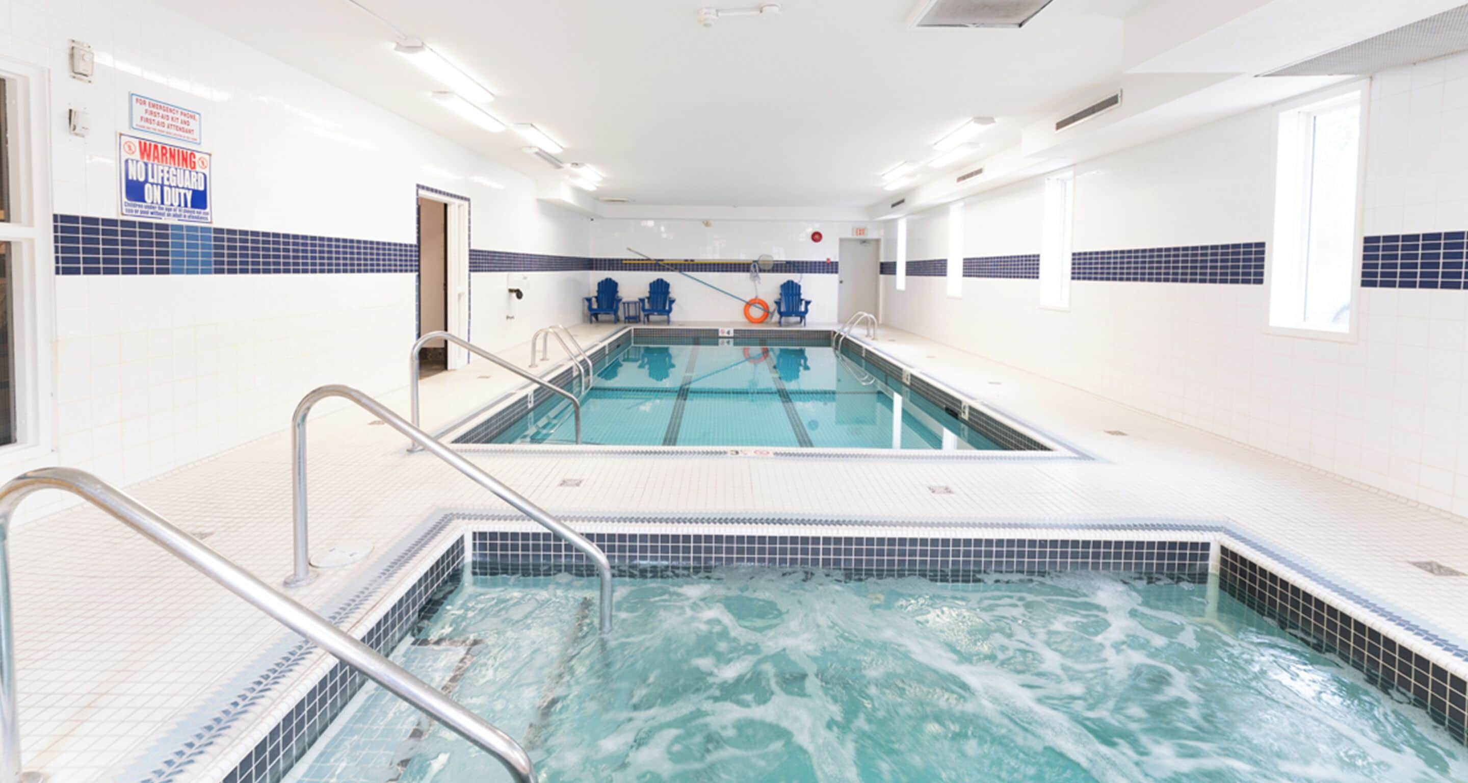 Una piscina con dos carriles, una silla de salvavidas y un letrero que indica que no hay salvavidas de servicio.