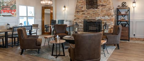 A modern lounge area with leather chairs, a stone fireplace, and a wooden floor.