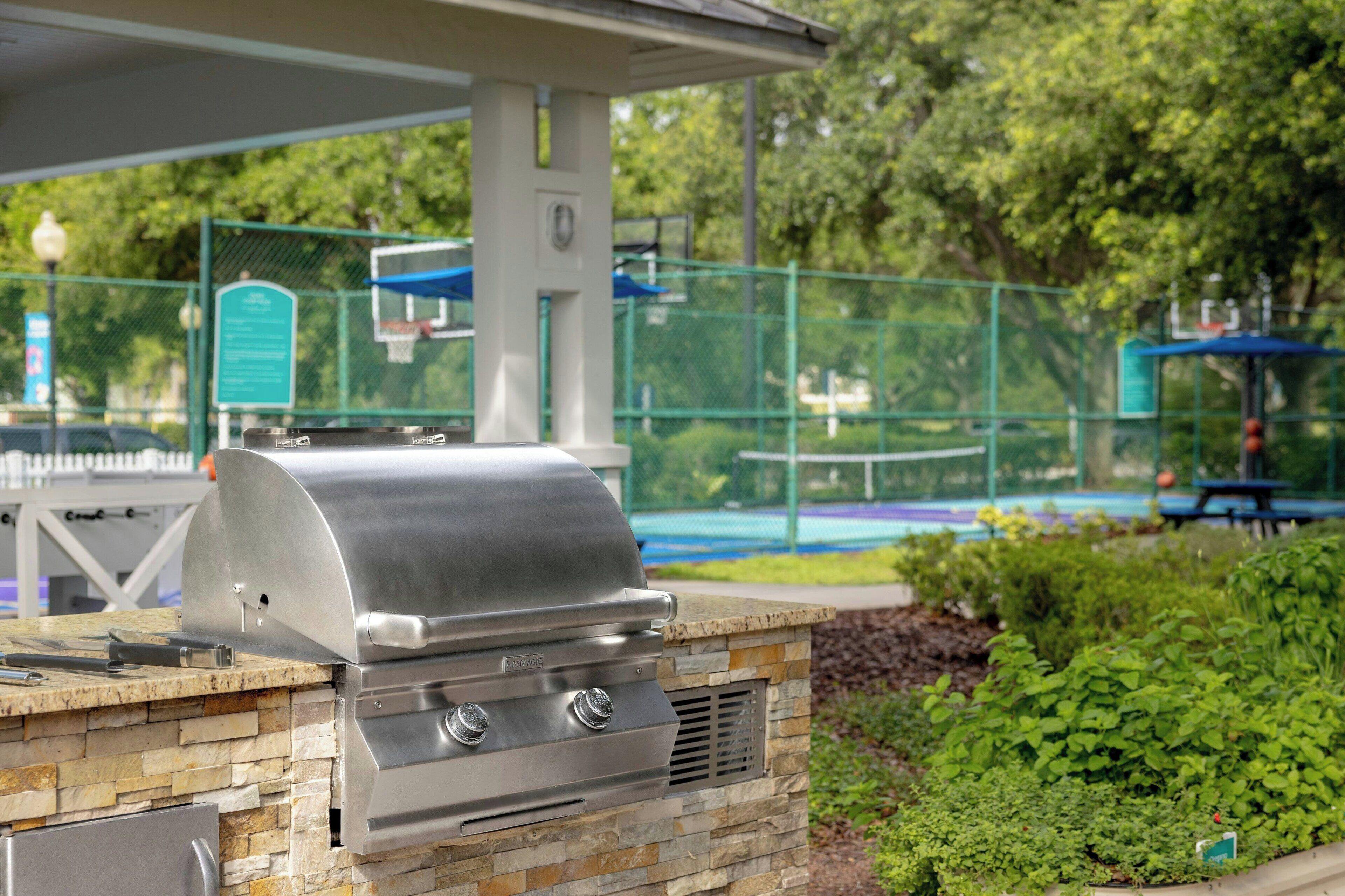 An outdoor grill with a stone base, a metal chimney, and a gas supply.