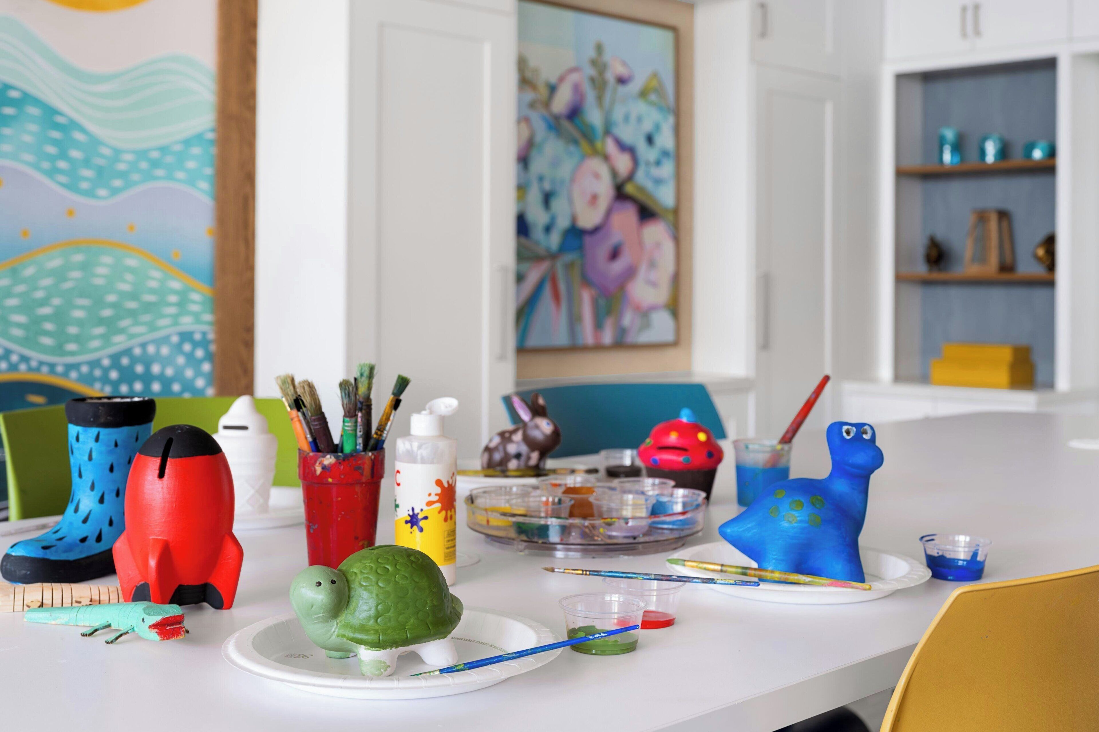 A kitchen counter with art supplies, a green turtle figurine, and a blue frog figurine.