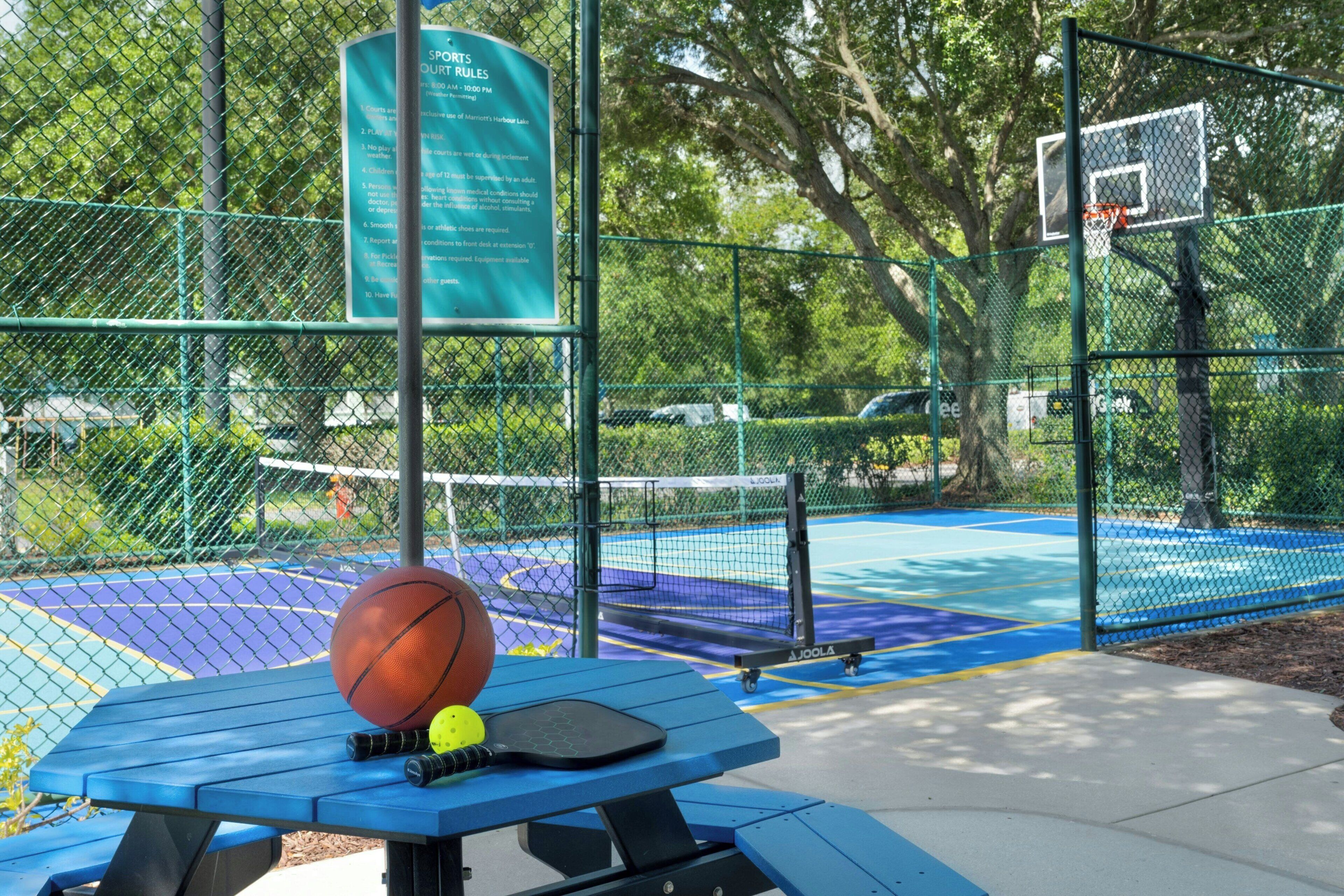 Una cancha deportiva al aire libre con una pelota de baloncesto, una pala y una mesa con equipo deportivo.