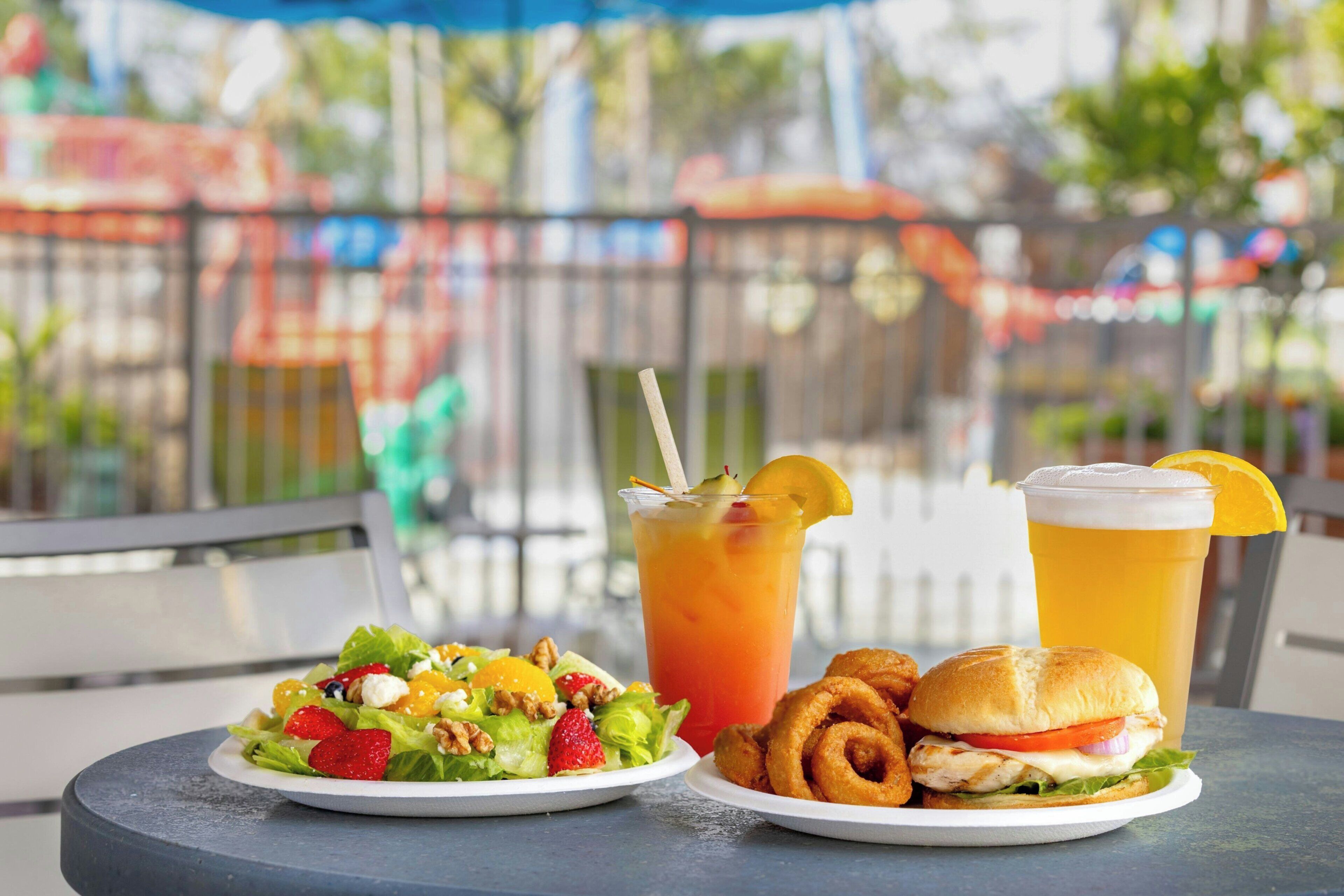 A table with a meal consisting of a salad, a drink, and a sandwich.
