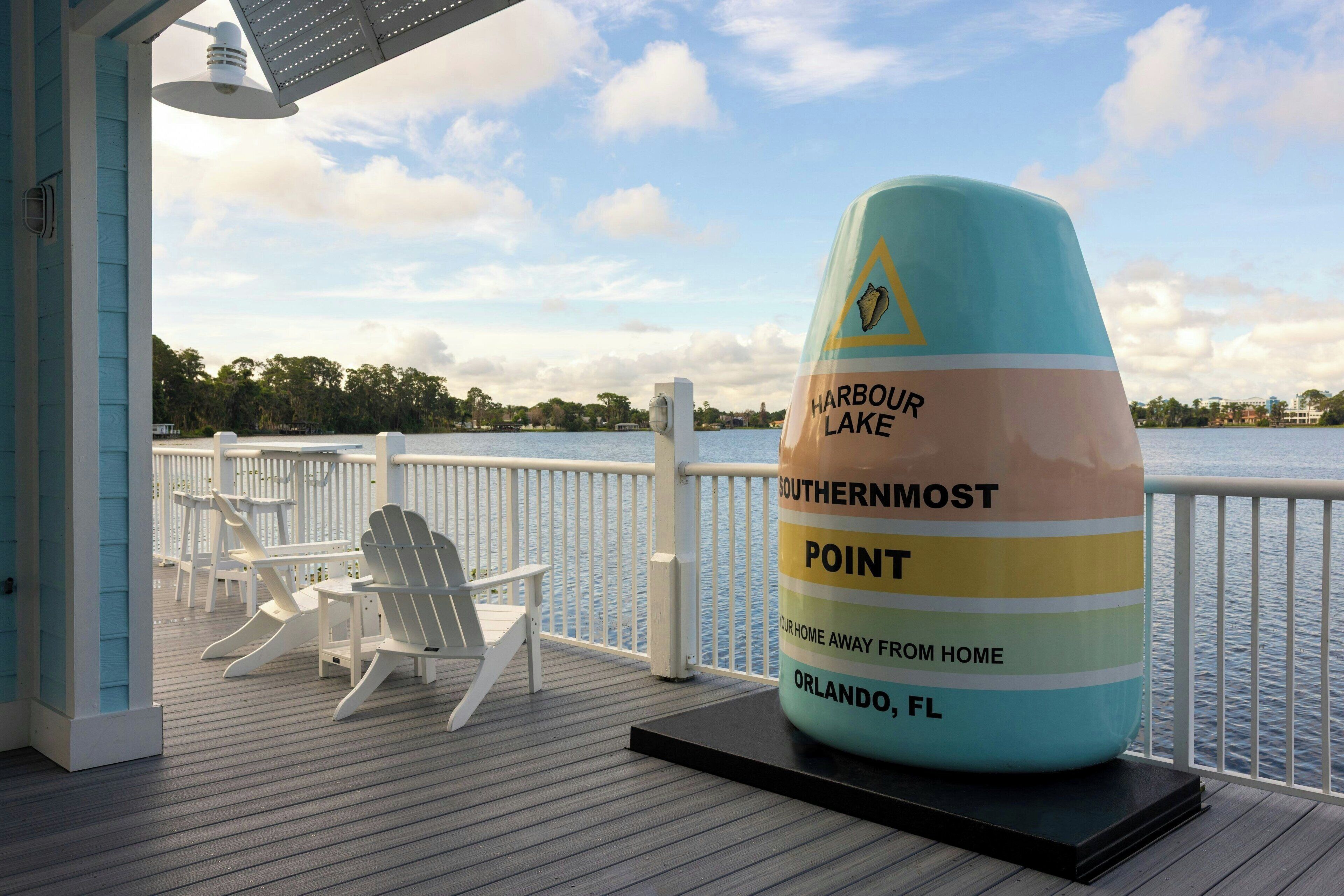 Una terraza con sillas Adirondack y un objeto decorativo grande que dice 'Harbour Lake Southernmost Point' en Orlando, Florida.