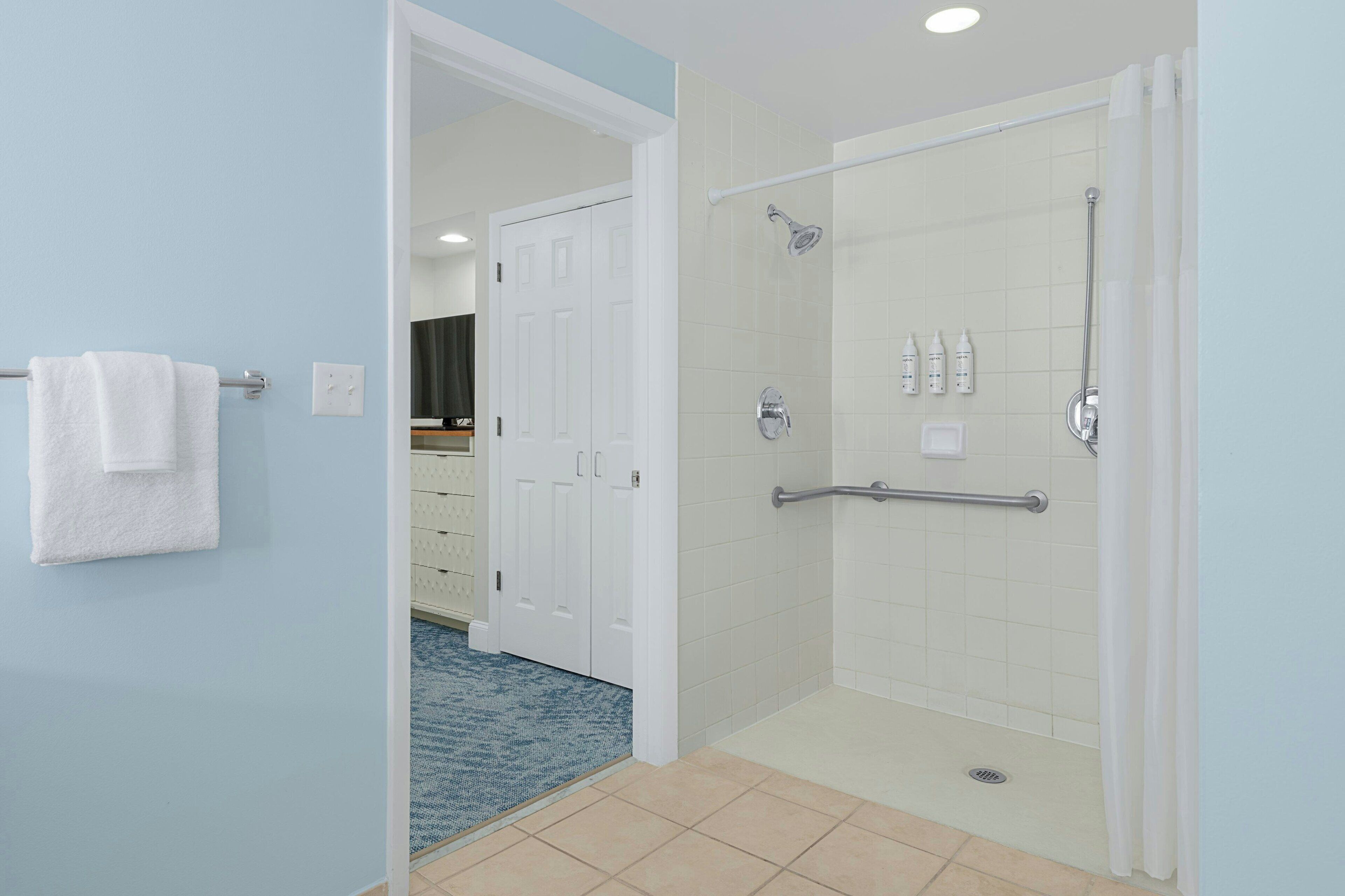 A modern bathroom with a walk-in shower, a white towel hanging on the wall, and a blue carpet.