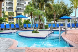 Relax by the pool surrounded by palm trees and lounge chairs.