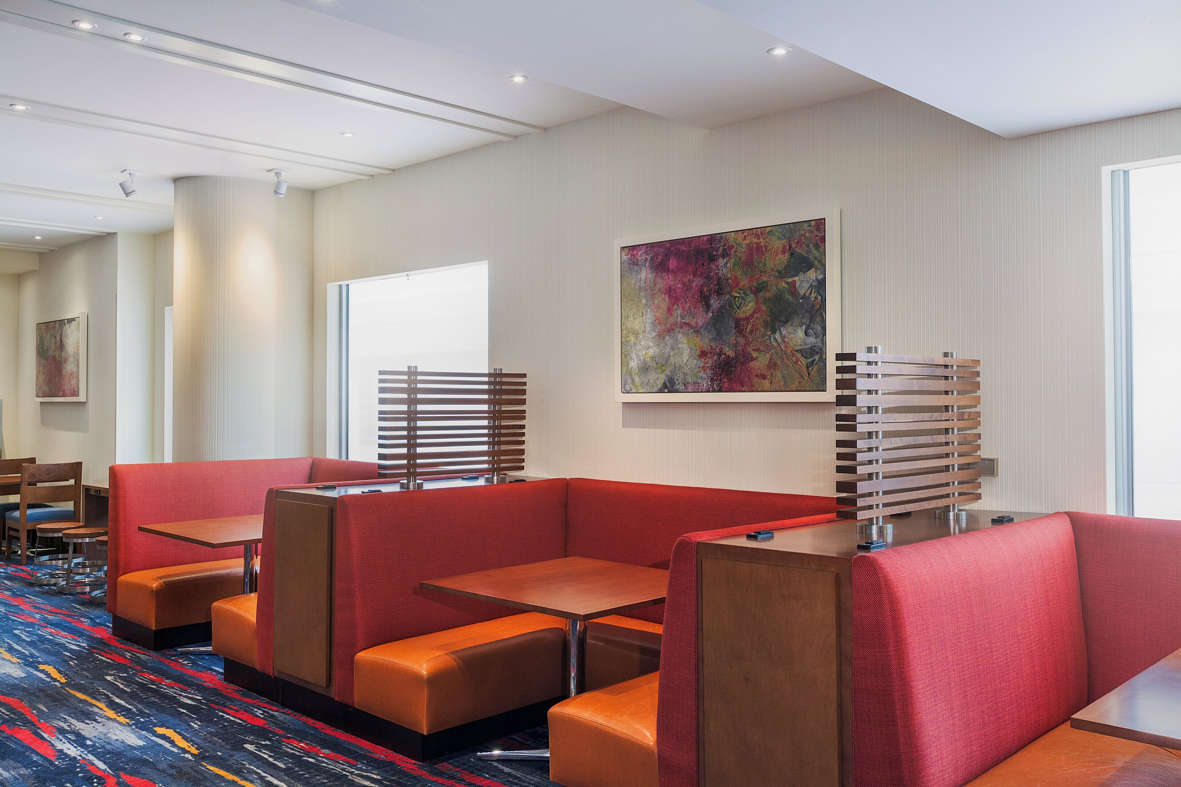 A hotel lobby with seating areas, a large abstract painting, and a patterned carpet.