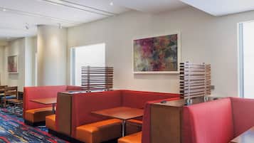 A hotel lobby with seating areas, a large abstract painting, and a patterned carpet.