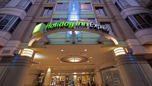 L’extérieur d’un hôtel Holiday Inn Express, avec une entrée bien visible, un panneau indiquant « Entrée réservée aux clients » et « Ouvert de 9h à 18h », et le nom de l’hôtel affiché en évidence.