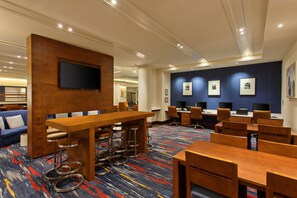 A modern hotel lobby with a wooden reception desk, bar stools, and a seating area with blue sofas. - Holiday Inn Express and Suites Fisherman's Wharf by IHG (San Francisco)