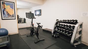 Uma academia com equipamentos de ginástica, televisão e um letreiro fixado na parede.