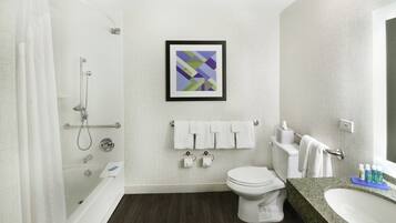 Un baño con ducha, inodoro, lavabo y una obra de arte abstracta enmarcada en la pared.