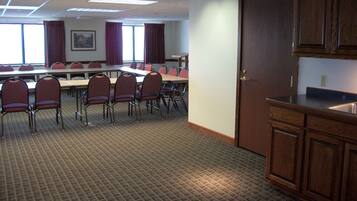 A conference room with a long table, chairs, and a kitchenette area.