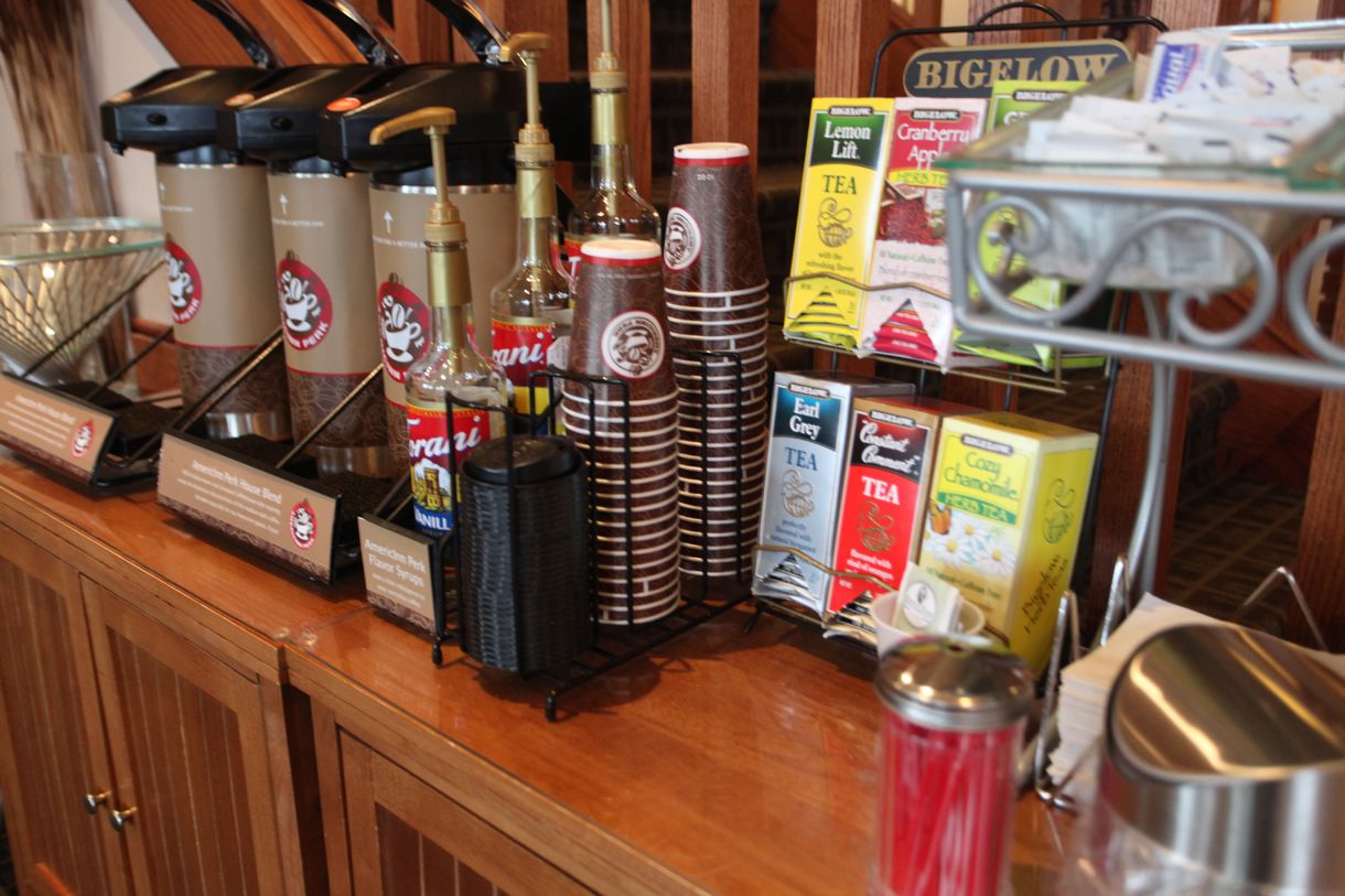 Una estación de café con varios dispensadores, un molinillo y diferentes cápsulas y recipientes para café.