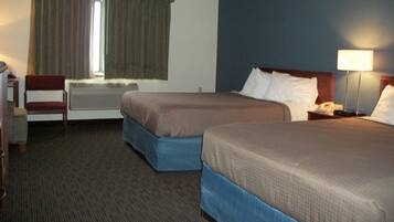 A hotel room with two beds, a chair, a desk, and a window with curtains.
