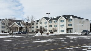 Un hotel con varias construcciones, estacionamiento y nieve en el suelo.